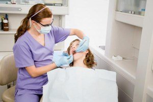 Стоматолог лечит зубы пациенту